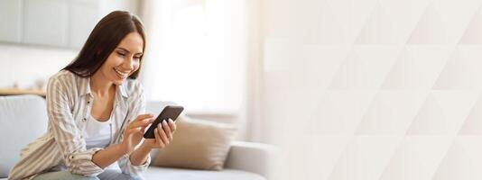 Smiling Young Woman Using Smartphone While Resting On Couch At Home, Happy Millennial Lady Sitting On Sofa And Using Mobile Phone, Shopping Online Or Browsing Social Networks, Copy Space photo