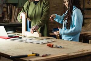 Carpenter making wooden frame while talking to client photo