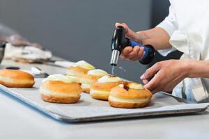Crop cook burning cream on dessert with gas burner in bakery photo