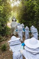Company of kids in protective costumes in apiary photo