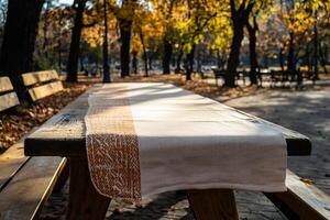Empty wooden picnic table with cream tablecloth in autumn park photo
