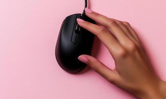 Hand using black computer mouse on pink background photo