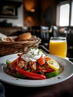 Grilled chicken with peppers and creamy topping served on a plate with a side of bread and orange juice photo