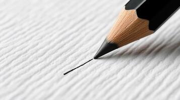 Close-up of a dark grey colored pencil drawing a precise line on textured paper photo