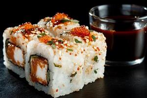 Fresh sushi rolls, topped with colorful fish and sesame seeds, served with soy sauce photo