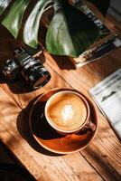 Latte art, camera, and nature-inspired workspace photo
