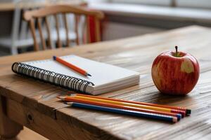 Classroom desk with notebook, pencils and apple photo