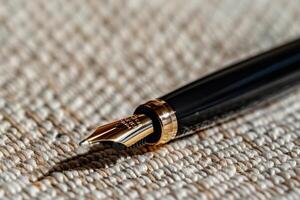 Close-up of a black fountain pen with gold nib on textured fabric photo