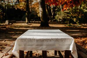 Empty wooden picnic table with white tablecloth in autumn park photo