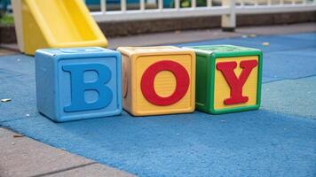 Colorful letter blocks that form the word boy in a playground setting during daylight hours photo