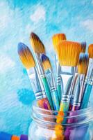 Collection of paintbrushes in glass jar with colorful tubes suggests artistic expression and studio use for art projects photo