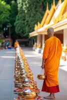 Monk receives alms in a serene temple courtyard surrounded by golden statues and traditional Buddhist decorations during morning rituals photo