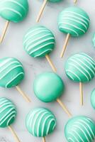 Glossy turquoise candy apples with wooden sticks artfully placed on a white marble surface highlighting their glossy finish and playful design photo