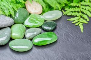 Elegant arrangement of polished green jade stones, soft moss, and delicate fern leaves creates a natural and calming aesthetic in a serene setting photo