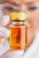 Scientist examines transparency of peptide-based drug in vial while wearing gloves in laboratory setting focused on pharmaceutical research photo