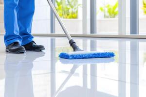 Janitorial worker in blue uniform expertly mopping glossy floor for a streak-free shine in a clean modern environment photo