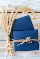 Handmade invitation set featuring navy blue envelopes with wheat embellishments and gold calligraphy on rustic wood photo