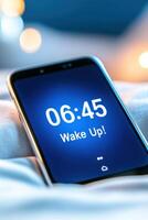 Smartphone alarm screen displaying 06.45 Wake Up reminder on cozy bed with soft morning light and snooze options photo