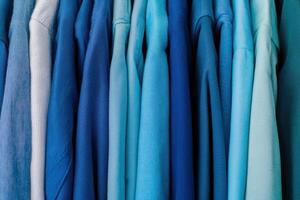 Monochrome wardrobe rack showcasing a gradient of clothing in various shades of blue from light to deep Little Boy Blue arranged neatly in a stylish display photo