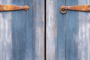 Old gray barn door with weathered textures and rusted hinges set against a rural countryside background showcasing natures beauty and timeless charm photo