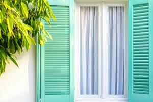 Dreamy garden window with teal shutters and sheer curtains invites tranquility and nostalgia in a French setting photo