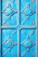 Antique French architectural door with intricate carvings in faded blue and teal tones, illuminated by atmospheric lighting, showcasing peeling paint and weathered charm photo