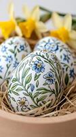 Hand-painted easter eggs with floral motifs resting in a bowl with daffodils in the background photo