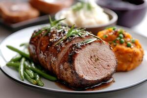 Sliced pork tenderloin with rosemary and spices, served with mashed potatoes, green beans and mashed sweet potatoes photo