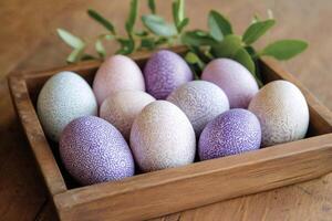 Decorative easter eggs with purple and pink patterns resting in wooden box photo