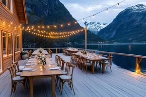 Wedding reception venue overlooking fjord in norway with string lights illuminating tables photo