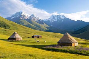 Yurts and sheep grazing on green meadow with snowy mountains in background photo