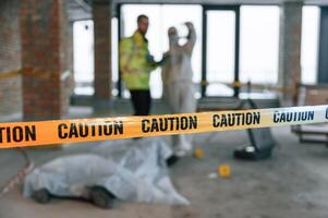 Detectives ,are collecting evidence in a crime scene, near dead body. Forensic specialists are making expertise photo