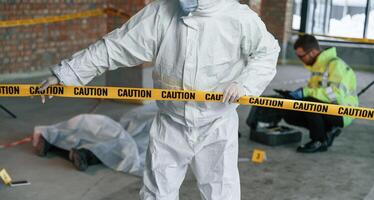 Holding ,caution, police tape.. Detectives are collecting evidence in a crime scene near dead body photo