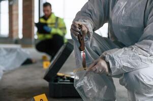 Putting,, the knife into bag. Detectives are collecting evidence in a crime scene near dead body photo