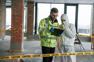 Reading document together. Detectives are collecting evidence in a crime scene near dead body photo