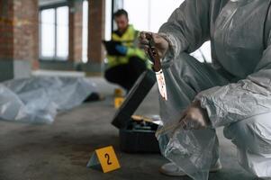 Putting ,the knife into bag. Detectives are collecting evidence in a crime scene near dead body photo
