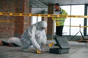 Knife as ,evidence. Blood is on the floor. Detectives are in a crime scene near dead body photo