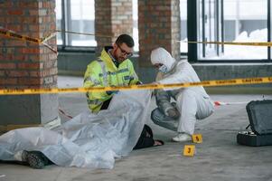 Dead body ,is on the ground. Detectives are collecting evidence in a crime scene photo