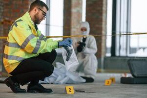 Woman,, is using camera, making photos. Detectives are collecting evidence in a crime scene near dead body photo