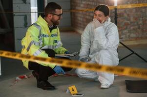 Sitting, and laughing. Two detectives are collecting evidence in a crime scene. Forensic specialists are making expertise photo