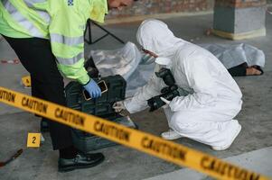 Caution police tape. Detectives are collecting evidence in a crime scene near dead body photo