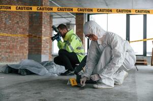 Knive and, blood is on the ground. Detectives are collecting evidence in a crime scene near dead body photo