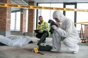 Knive ,,and blood is on the ground. Detectives are collecting evidence in a crime scene near dead body photo
