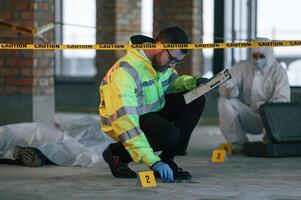 Knife clue. Detectives, are collecting evidence in a crime scene near dead body. Forensic specialists are making expertise photo