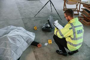 Notepad with information.. Male detective is collecting evidence in a crime scene near dead body on the construction site photo