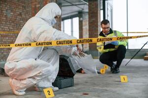 Woman ,holds the sleeve from the cartridge and puts it in the bag. Detectives are collecting evidence in a crime scene near dead body photo