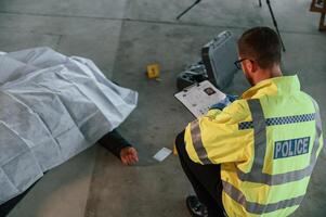 Notepad with, information. Male detective is collecting evidence in a crime scene near dead body on the construction site photo