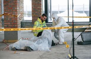 At daytime. Detectives, are ,collecting evidence in a crime scene near dead body photo