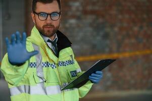 No trespassing, stop gesture by a hand. Male detective is collecting evidence in a crime scene on the construction site photo