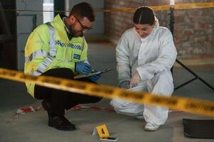 Sitting and laughing. Two detectives are collecting evidence in a crime scene. Forensic specialists are making expertise photo